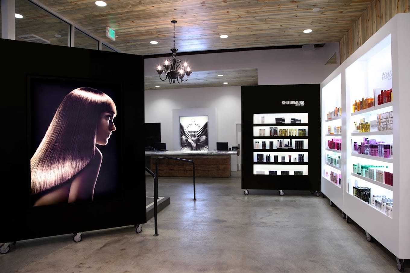 Hair salon interior with product displays and a large photo of a woman with sleek hair.